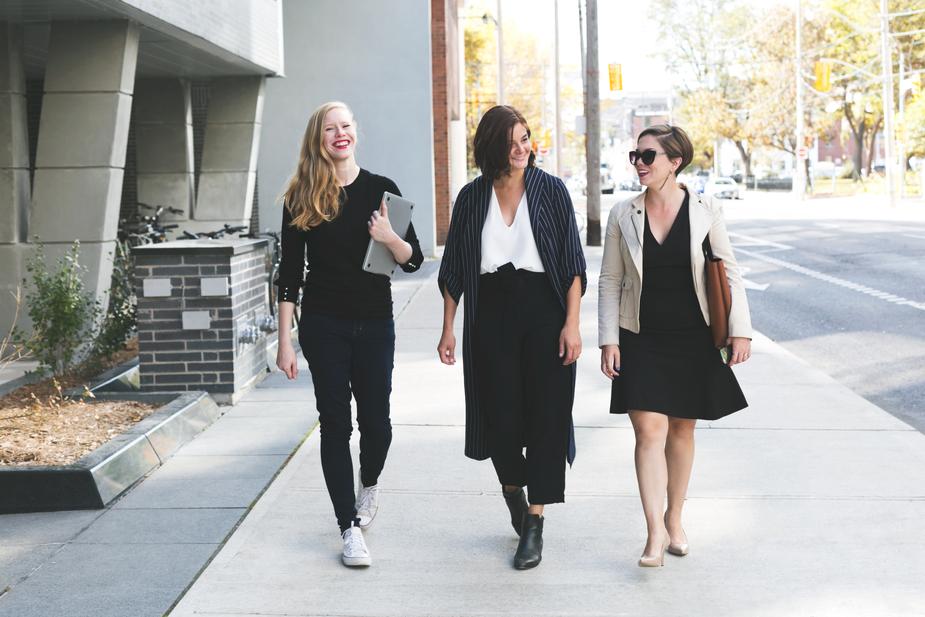 Three women dressed in business professional clothes walking and smiling with each other