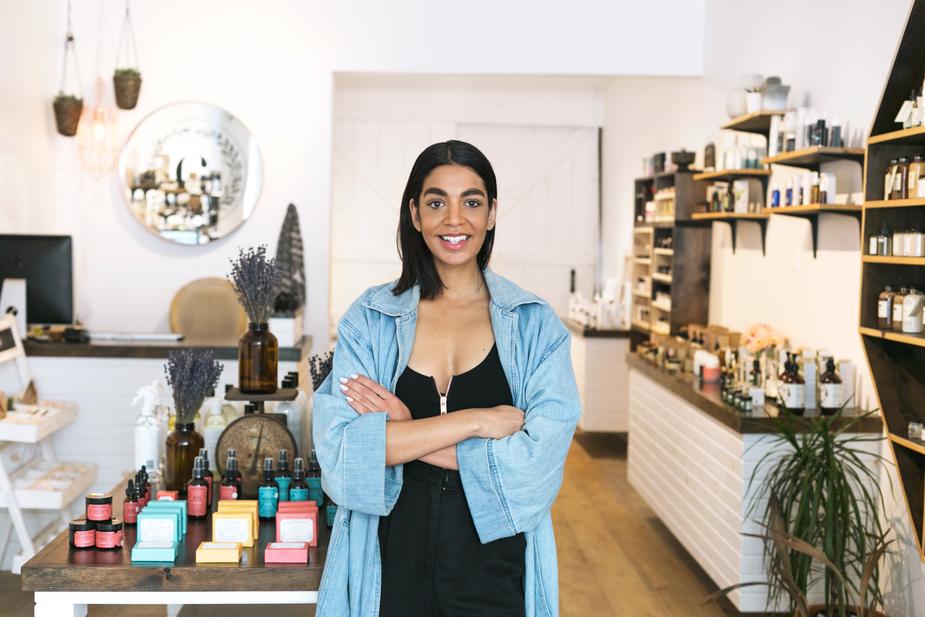 A woman business owner standing in her shop, looking proud and accomplished.