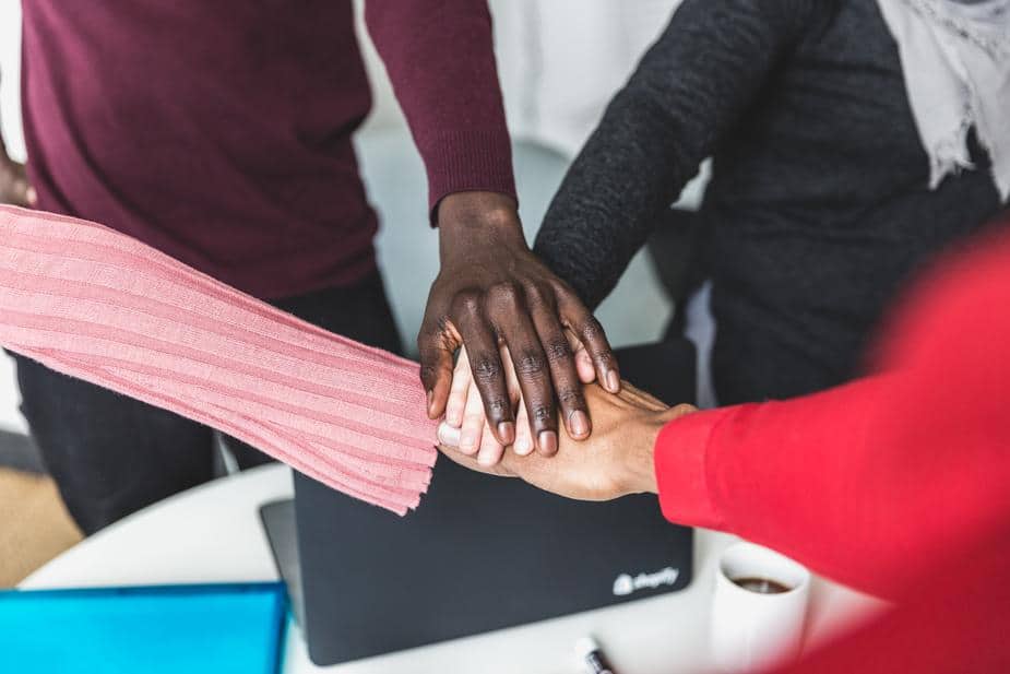 Team's hands together, showing teamwork and accomplishment.